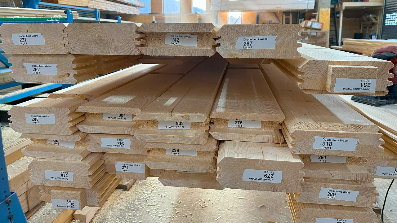 Stapel von präzise zugeschnittenen Blockbohlen für Holzhäuser, bereit für den Versand durch den Hersteller FINNHOLZ.