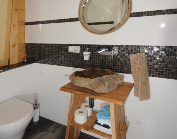 Natürliches Badezimmerdesign in einem FINNHOLZ Blockbohlenhaus mit Holzelementen und modernen Akzenten.