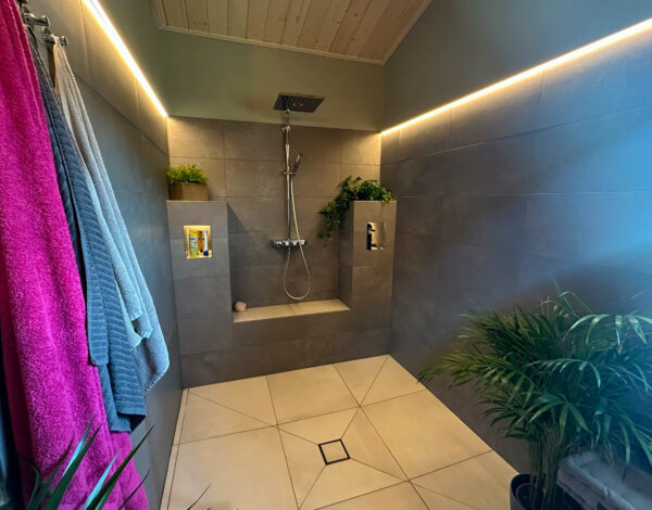 Modernes FINNHOLZ Blockhaus-Badezimmer mit stimmungsvoller Beleuchtung und stilvoller Regendusche.
