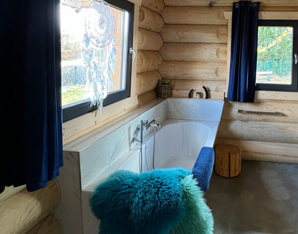 Entspannendes Badezimmer mit freistehender Badewanne in einem FINNHOLZ Rundbohlen-Blockhaus.