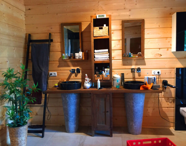 Badezimmer im FINNHOLZ Blockbohlenhaus mit natürlichen Materialien und rustikalem Waschtisch.