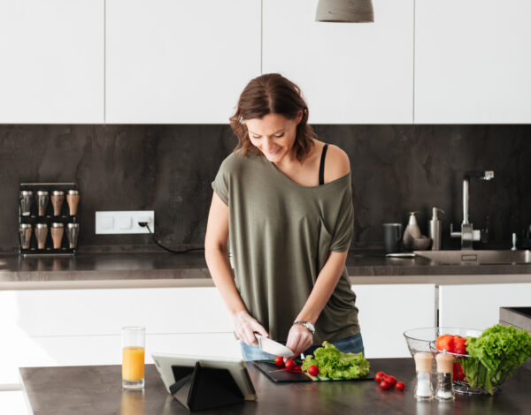 Frau bereitet frischen Salat in der modernen, stilvollen Küche eines FINNHOLZ Blockhauses zu.