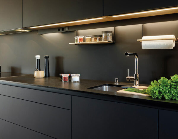 Schicke dunkle Kücheneinrichtung in einem modernen FINNHOLZ Blockhaus mit stimmungsvoller Beleuchtung.
