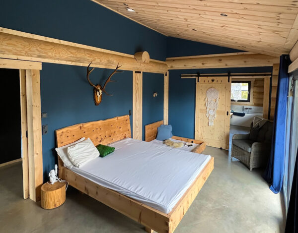 Schlafzimmer mit massiven Holzelementen in einem Rundbohlen-Blockhaus von FINNHOLZ.