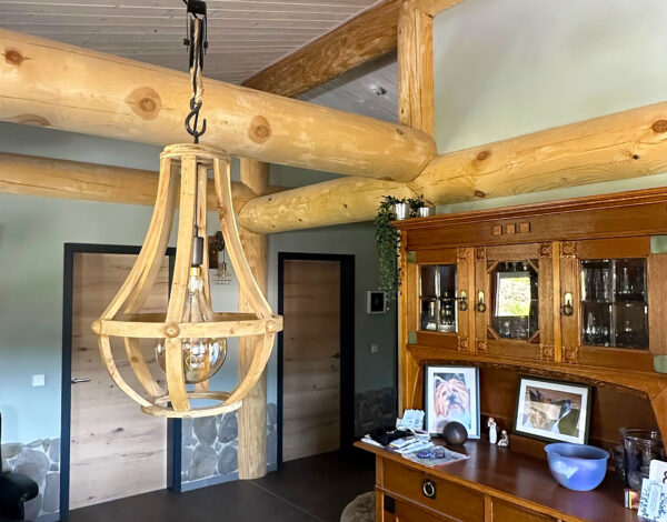 Charmanter Wohn- und Essbereich eines FINNHOLZ Post-and-Beam-Hauses mit rustikaler Holzbalkenarchitektur und eleganter Hängeleuchte.