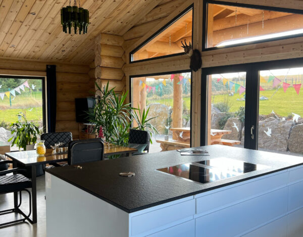 Stilvolles Wohnzimmer mit moderner Kücheninsel in einem FINNHOLZ Rundbohlen-Blockhaus.