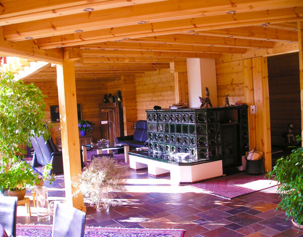 Geräumiges Wohnzimmer mit traditionellem Kamin und Holzbalken in einem FINNHOLZ Blockhaus.