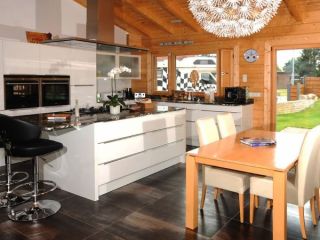 Offene Küchen- und Essbereichsgestaltung in einem FINNHOLZ Blockbohlenhaus mit modernen Einrichtungen und Holzbalken.