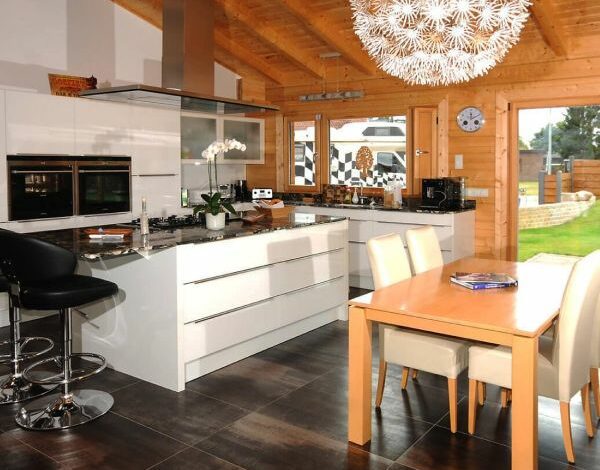 Offene Küchen- und Essbereichsgestaltung in einem FINNHOLZ Blockbohlenhaus mit modernen Einrichtungen und Holzbalken.