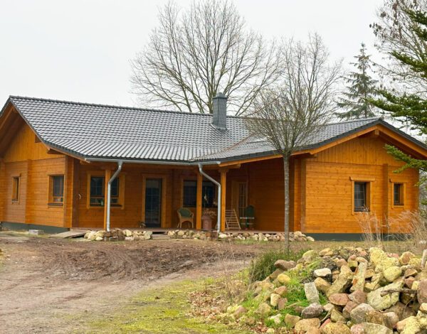 Gemütliches Blockbohlenhaus von FINNHOLZ mit überdachter Veranda und naturnaher Umgebung.