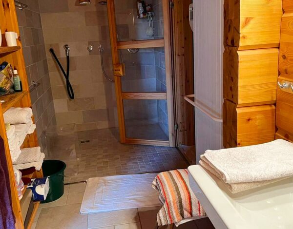 Hell und freundlich gestaltetes Badezimmer im FINNHOLZ Blockhaus mit natürlicher Holzverkleidung und moderner Dusche.