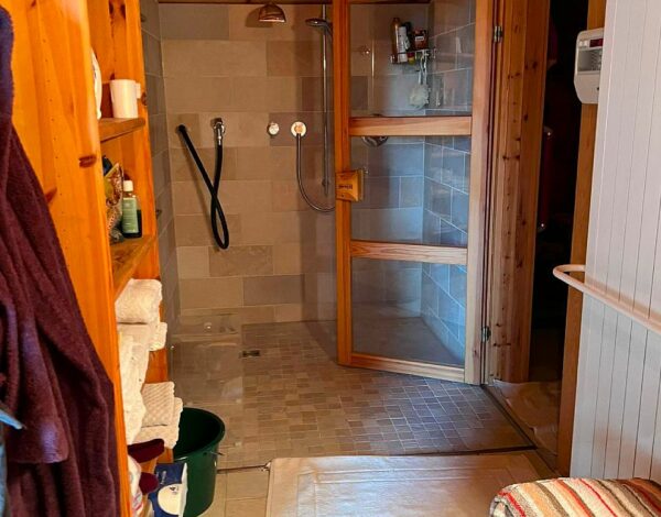 Duschbereich mit natürlicher Holzverkleidung in einem FINNHOLZ Blockhaus.