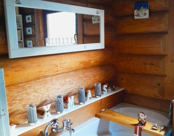 Gemütliches Badezimmer mit Badewanne im FINNHOLZ Rundbohlenhaus, dekoriert mit Weihnachtsmotiven.