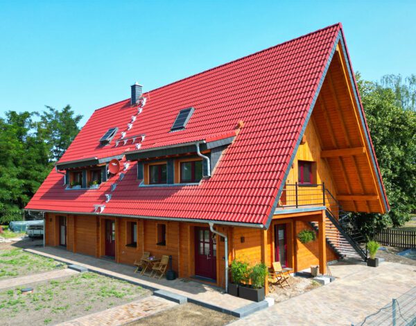 Traditionelles FINNHOLZ Blockbohlenhaus mit rotem Dach und gemütlicher Holzfassade.