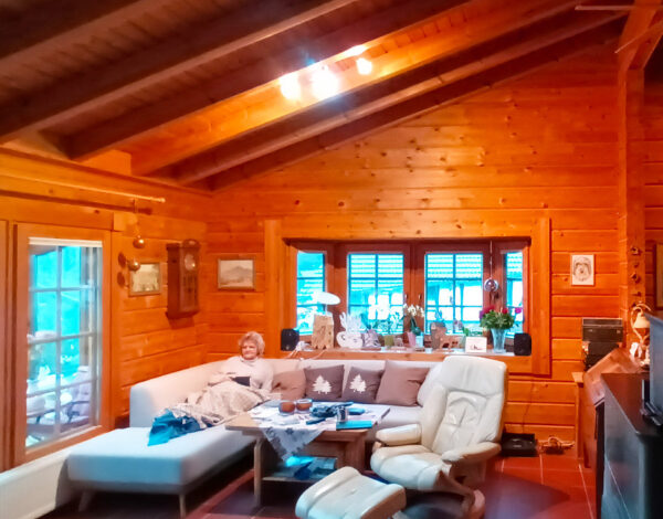 Komfortables Wohnzimmer in einem FINNHOLZ Blockhaus mit Blockbohlenwänden, gemütlichen Möbeln und einem rustikalen Ambiente.