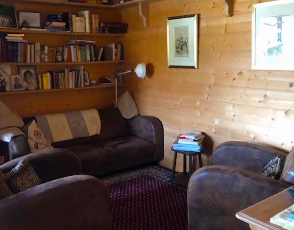 Behagliches Wohnzimmer in einem FINNHOLZ Blockhaus mit gemütlichen Sofas und einer gut bestückten Bücherwand.