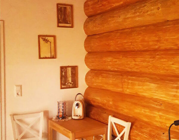Kleine Essecke mit weiß gestrichenen Stühlen und Holztisch in der gemütlichen Küche eines FINNHOLZ Rundbohlenhauses.