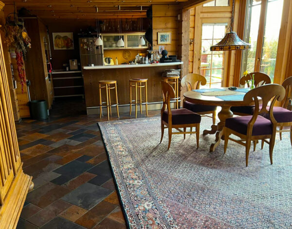 Essbereich in einem FINNHOLZ Blockhaus mit offener Küche, elegantem Holztisch und gemütlicher Atmosphäre.