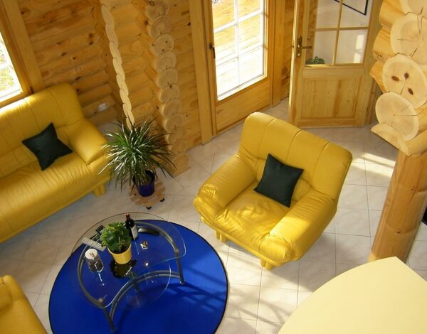 Helles Gästezimmer mit gelben Sofas und Sessel in einem Blockhaus von Finnholz.