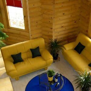 Verschiedene Blickwinkel auf das helle Gästezimmer mit gelben Sofas und Sessel in einem Blockhaus von Finnholz.