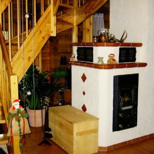 Ofen und Treppe im Vierkantbohlenhaus von Finnholz.