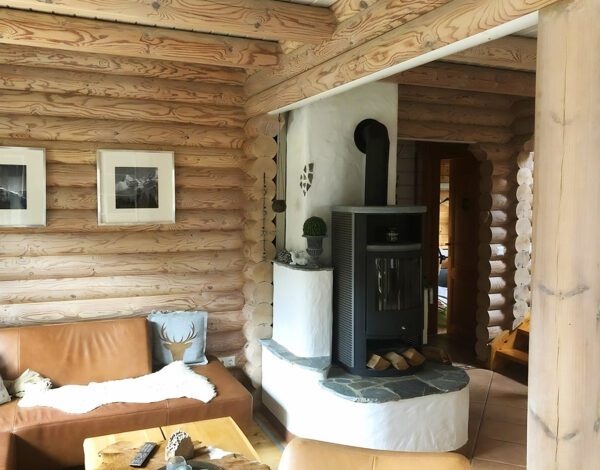 Gemütliches Wohnzimmer mit Kamin in einem Rundbohlenhaus von Finnholz.