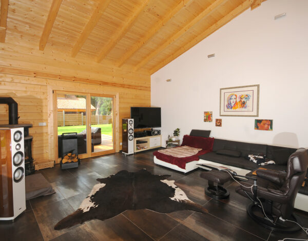 Wohnzimmer mit natürlicher Blockholzwand und modernen Möbeln im FINNHOLZ Blockhaus.
