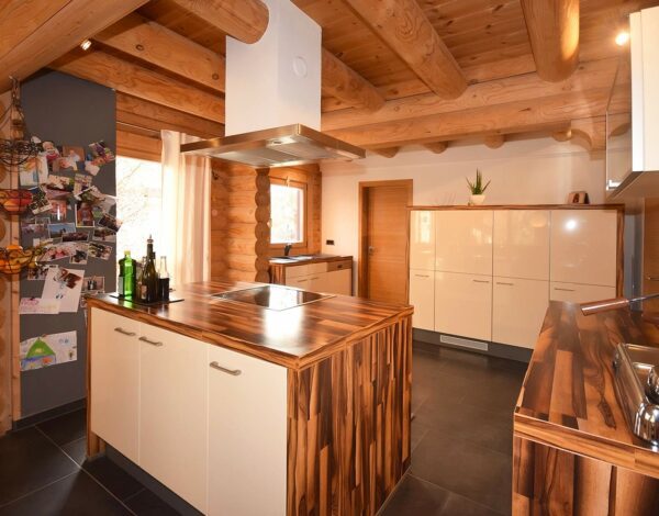 Innenansicht der geräumigen Küche mit zentraler Insel in einem Rundbohlenhaus von Finnholz.