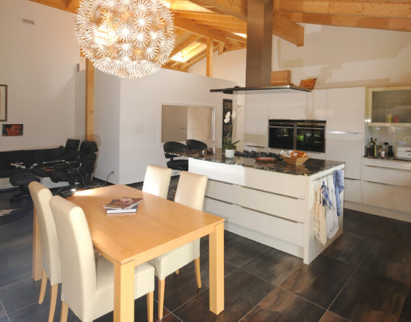 Luftiges Esszimmer mit integrierter Küche in einem hellen Blockbohlenhaus von FINNHOLZ.