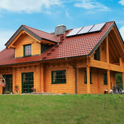 Energiesparendes Blockhaus von FINNHOLZ mit rotem Ziegeldach und Solaranlage.