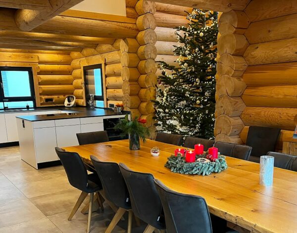 Gemütliches FINNHOLZ Blockhaus mit festlich geschmücktem Weihnachtsbaum, erbaut aus robusten Rundbohlen.