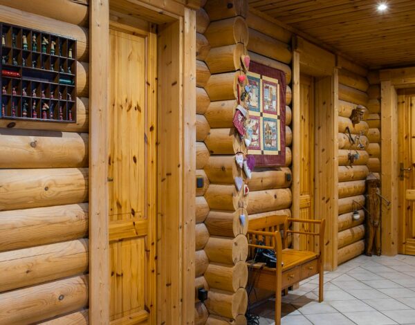Flur in einem Rundbohlen-Blockhaus von FINNHOLZ mit natürlicher Holzwand und dekorativen Elementen.