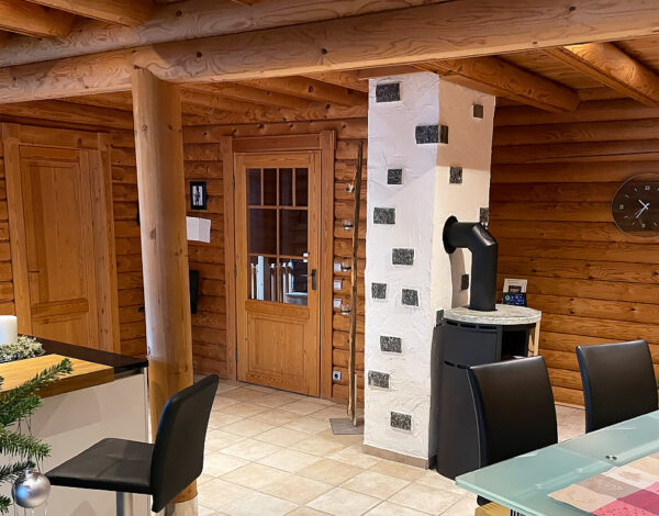Offener Wohn- und Essbereich in einem FINNHOLZ Rundbohlen-Blockhaus mit Weihnachtsdekoration, modernen Möbeln und klassischer Holzarchitektur.