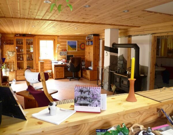 Gemütliches Wohnzimmer im Rundbohlen-Blockhaus von FINNHOLZ mit rustikalem Kaminofen und traditioneller Einrichtung.