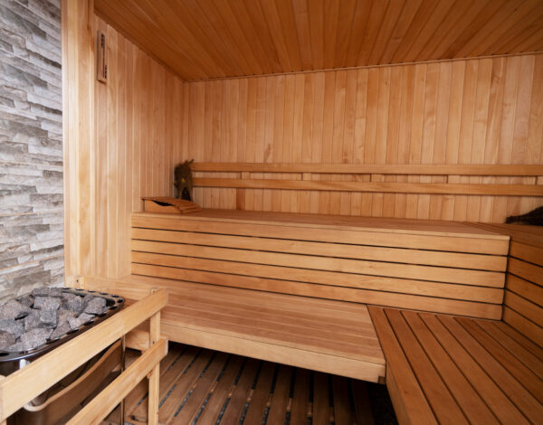Innenansicht einer Sauna im FINNHOLZ Blockhaus mit Holzliegen und Steinwand.