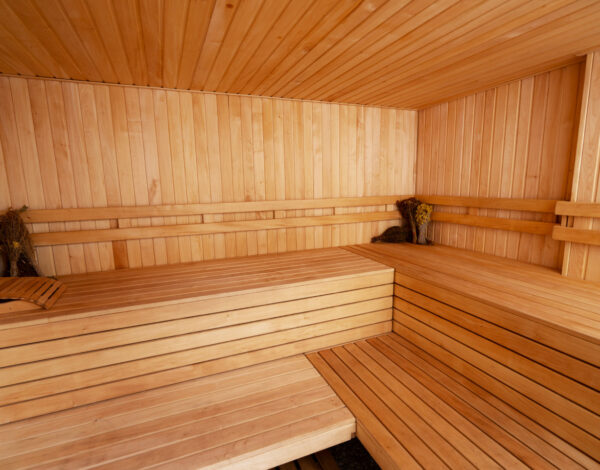 Hochwertige Sauna im Blockhaus von FINNHOLZ mit Steinwand und Holzliegen.