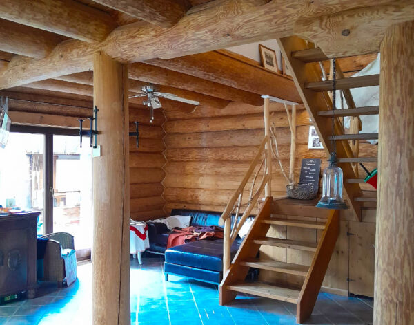 Offenes Wohnzimmer mit Holztreppen und Rundbohlenstruktur in einem FINNHOLZ Blockhaus.