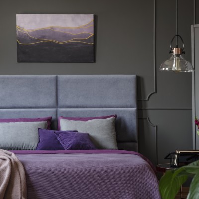 Stilvolles Schlafzimmer mit grauem Kopfteil und lila Akzenten in einem FINNHOLZ Fertighaus.