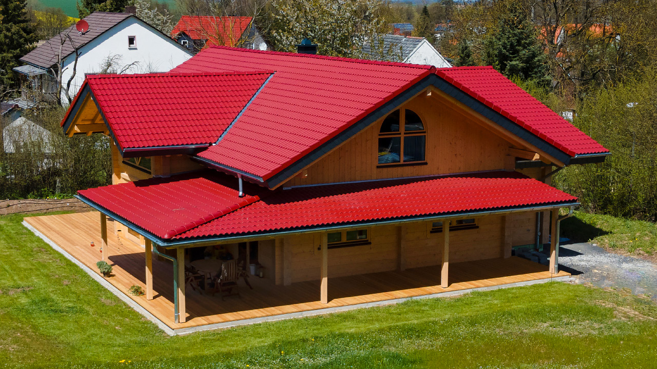 Modernes FINNHOLZ Holzhaus aus qualitativen Blockbohlen mit rotem Dach.