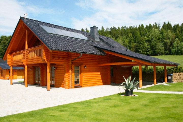 Rundbohlen-Blockhaus von FINNHOLZ in idyllischer Naturlandschaft mit Solarpanelen.