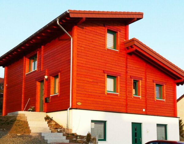 Leuchtend rotes FINNHOLZ Blockbohlenhaus mit moderner Ausstrahlung.