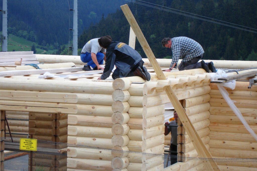 Arbeiter beginnen mit der Verlegung von Holzpaneele auf den Deckenbalken, um den ersten Stock zu decken und die Basis für die Zwischendecke zu schaffen.