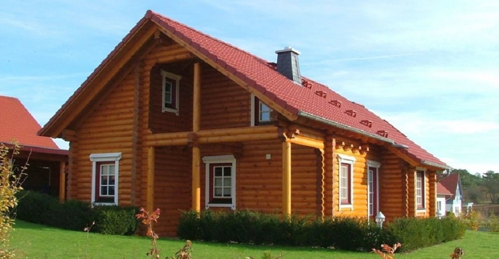 Ein traditionelles FINNHOLZ Blockhaus mit grünem Rasen und blauem Himmel im Hintergrund.