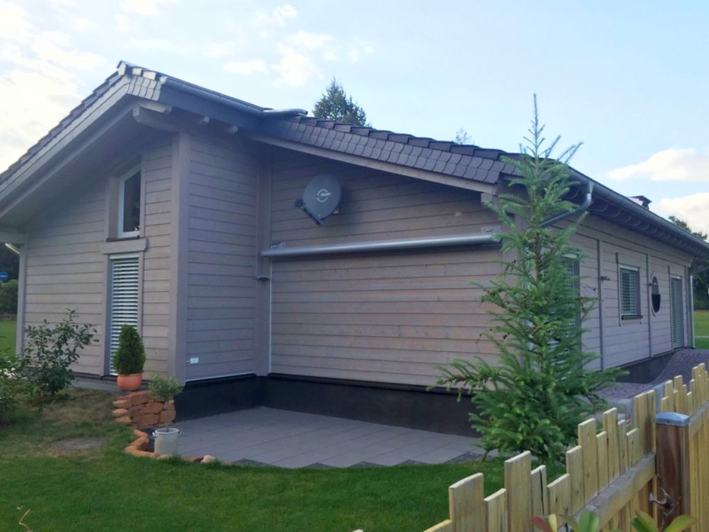 Grau gestrichenes Finnholz-Blockhaus-Bungalow auf einem gepflegten Grundstück, KfW40-konform.