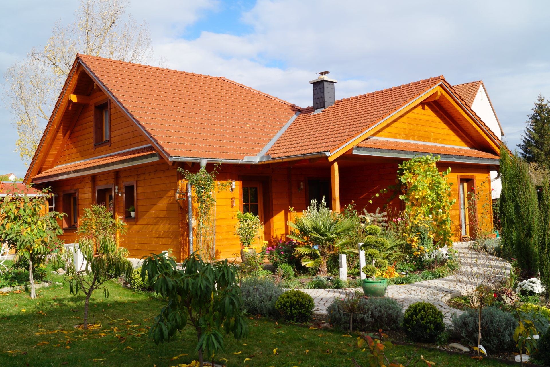 Holzhaus von Finnholz mit rotem Dach, umgeben von einer vielfältigen Gartenlandschaft.