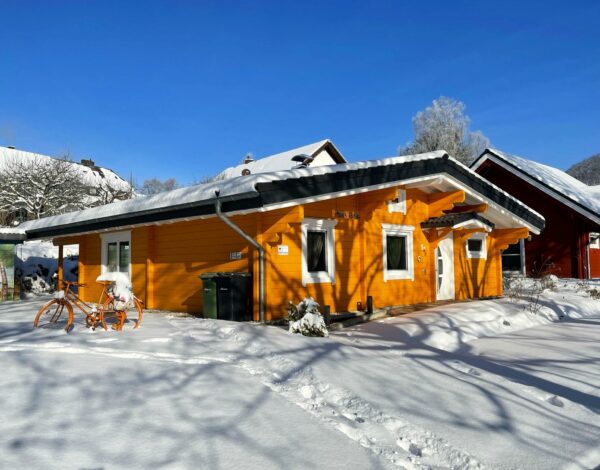 Schneebedecktes Blockhaus von Finnholz in leuchtendem Orange.