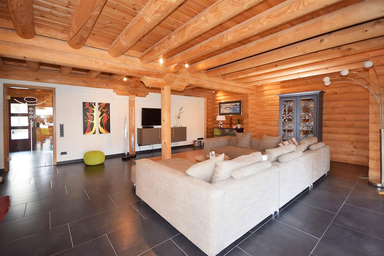 Modernes Wohnzimmer im FINNHOLZ Rundbohlen-Blockhaus mit eleganten Holzdetails und stilvollem Design.