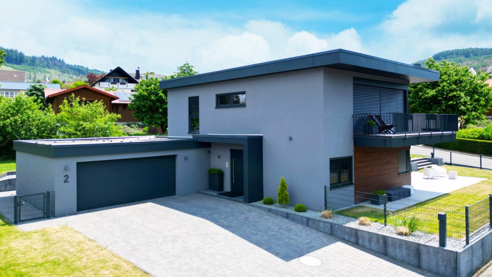 Modernes Fertighaus von FINNHOLZ mit flachem Dach und stilvoller Außenfassade in einer grünen Wohngegend.